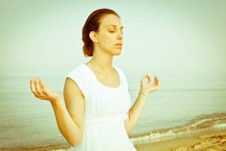 Beautiful Young Woman Doing Yoga Exercises at Seasideの写真素材