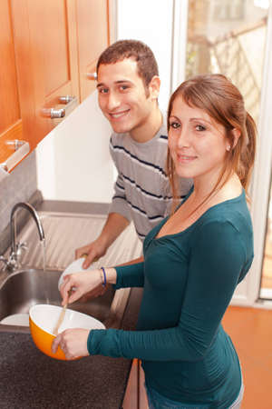 Wife Cooking While Husband Washing Dishesの写真素材