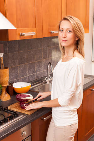Young Woman in the Kitchen Cutting Vegetablesの写真素材