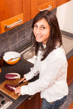 Young Woman in the Kitchen Cutting Vegetablesの写真素材