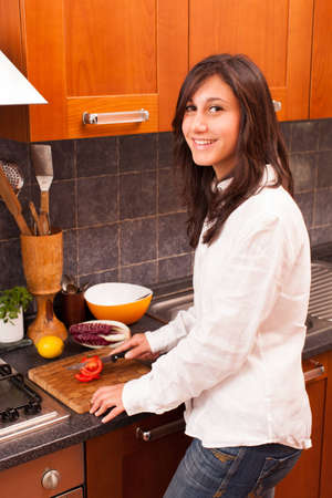 Young Woman Cutting Tomato in the Kitchenの写真素材