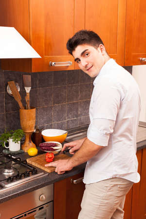 Man Cutting Tomato in the Kitchenの写真素材