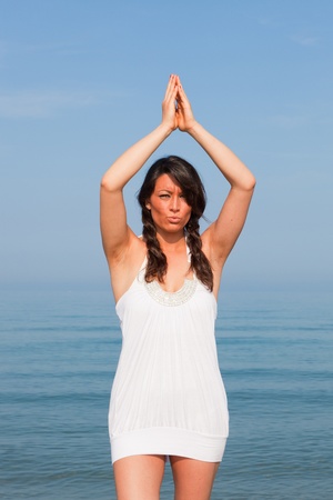 Beautiful Young Woman Doing Yoga Exercises at Seasideの写真素材