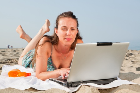 Woman Working at Computer on the Beachの写真素材