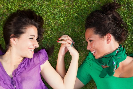 Two Girls Lying on the Grass and Holding Handsの写真素材