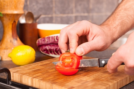 Man Cutting Tomato in the Kitchenの写真素材