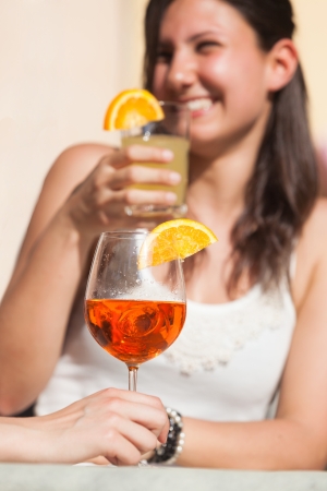 Happy Young Woman Drinking with Cold Drink in Foregroundの写真素材