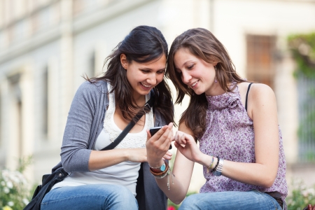 Two Beautiful Women Sending Messages with Mobileの写真素材