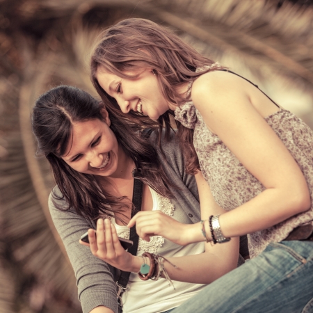 Two Beautiful Women Sending Messages with Mobileの写真素材