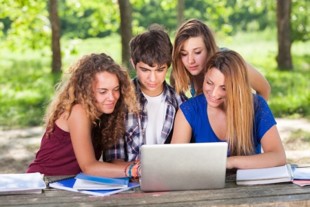 Group of Teenage Students at Park with Computer and Booksの写真素材