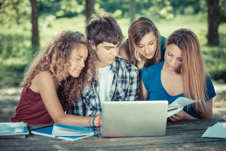 Group of Teenage Students at Park with Computer and Booksの写真素材