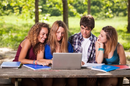 Group of Teenage Students at Park with Computer and Booksの写真素材