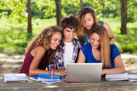 Group of Teenage Students at Park with Computer and Booksの写真素材
