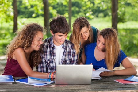 Group of Teenage Students at Park with Computer and Booksの写真素材
