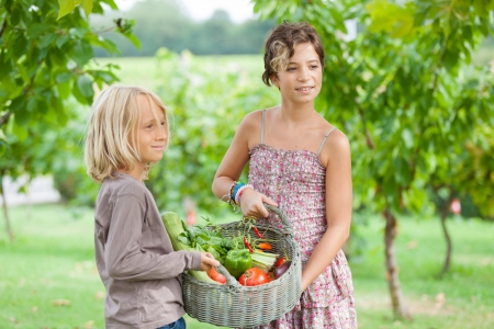 Boy and Girl Holding Basket of Vegetablesの写真素材
