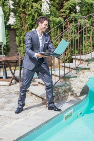 Angry Businessman with Computer next to Swimming Poolの写真素材