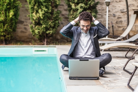 Young Businessman with Computer next to Swimming Poolの写真素材