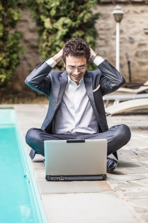 Young Businessman with Computer next to Swimming Poolの写真素材