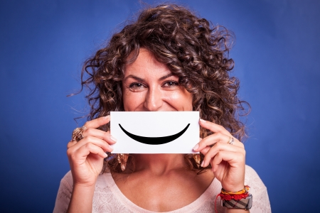 Young Woman with Smiley Emoticon on Blue Backgroundの写真素材