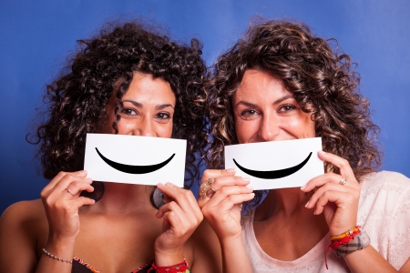 Two Young Women with Smiley Emoticon on Blue Backgroundの写真素材