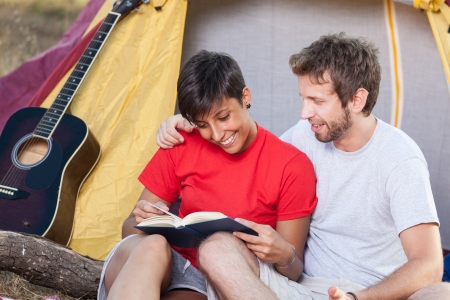 Young Couple Camping and Reading a Bookの写真素材