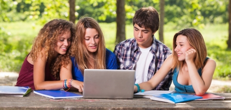 Group of Teenage Students at Park with Computer and Booksの写真素材