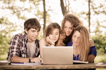 Group of Teenage Students at Park with Computer and Booksの写真素材