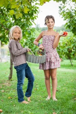Boy and Girl Holding Basket of Vegetablesの写真素材