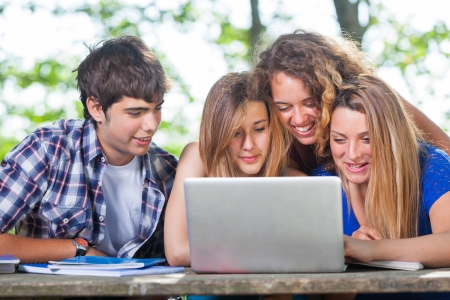 Group of Teenage Students at Park with Computer and Booksの写真素材