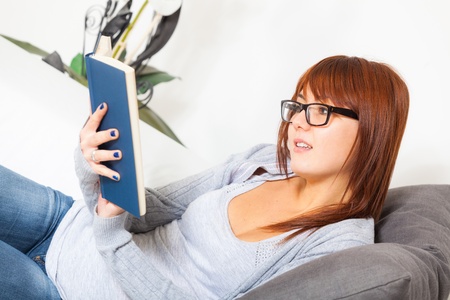 Beautiful Young Woman with a Book on the Sofaの写真素材