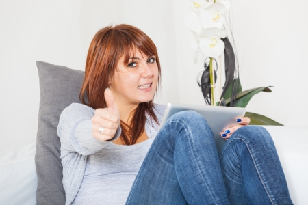 Beautiful Young Woman with Tablet PC on the Sofaの写真素材