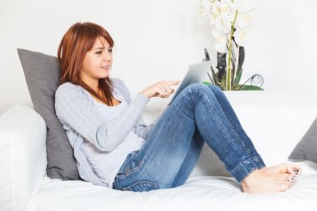 Beautiful Young Woman with Tablet PC on the Sofaの写真素材