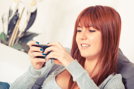 Beautiful Young Woman with Smartphone on the Sofaの写真素材