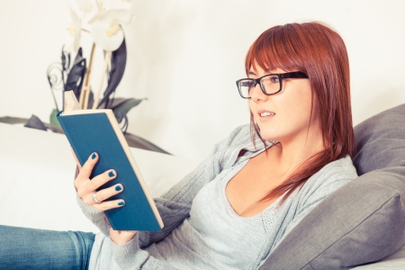 Beautiful Young Woman with a Book on the Sofaの写真素材
