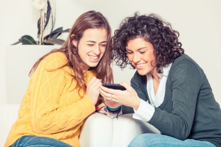 Two Beautiful Women with Mobile Phone in the Living Roomの写真素材