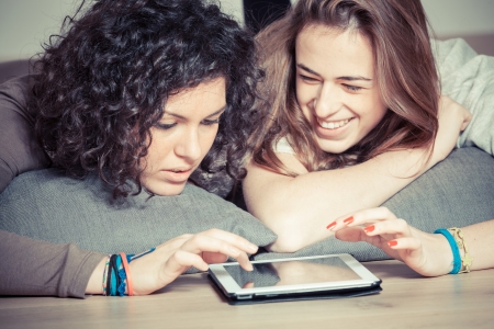 Two Beautiful Women with Tablet PC in the Bedroomの写真素材
