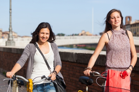 Two Beautiful Women Walking in the City with Bicycles and Bagsの写真素材