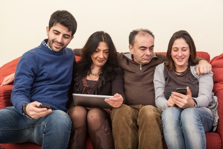 Happy Family on the Sofa with Electonic Devicesの写真素材
