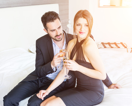 Elegant Young Couple Cheering at Hotel Suiteの写真素材