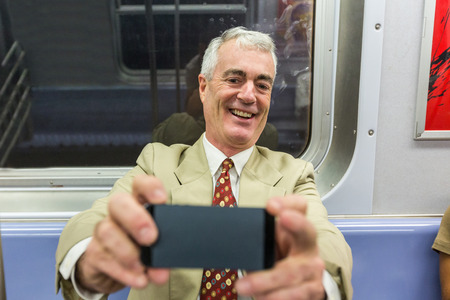 Senior Businessman Taking a Selfie in the Subway Train