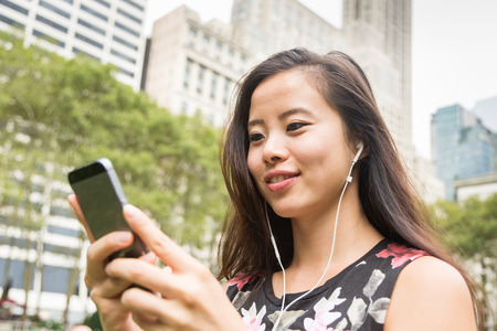 Beautiful Asian Young Woman with Mobile Phone and Earphonesの写真素材