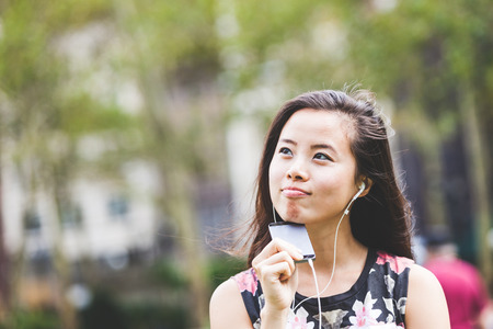 Asian Girl Listening Music at Parkの写真素材