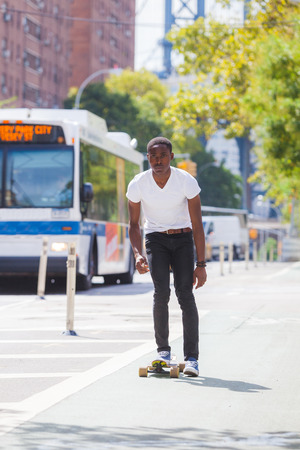 Black Boy Skating with Longboard on the Roadの写真素材