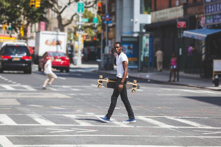 Black Boy Walking in the City Holding Longboardの写真素材