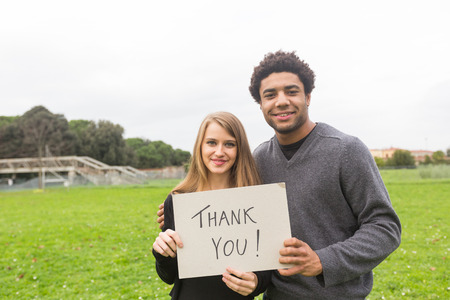 Multiethnic Couple Saying Tahnk You with a Boardの写真素材