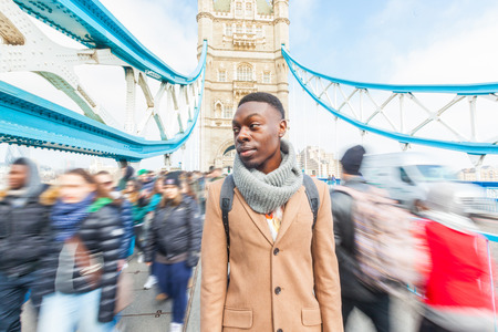 Man on Tower Bridge, London, with blurred people on background. He is looking away. Photo taken on a sunny winter day.の写真素材