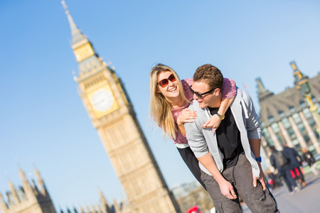 Happy young couple enjoying a piggyback ride in London with Big Ben amd Westminster palace on background. の写真素材
