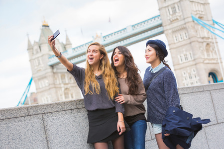 Multiracial group of girls taking a selfie in London with Tower Bridge on background. の写真素材