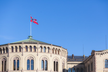 Norwegian flag on parliament building rooftop, with a blu sky on a sunny day.の写真素材