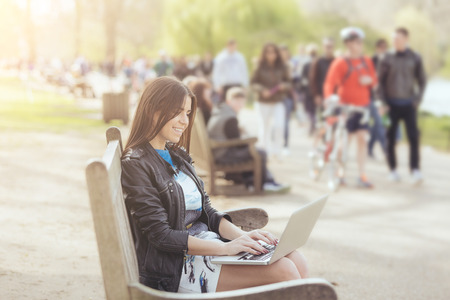 Young woman using computer at park in London. の写真素材